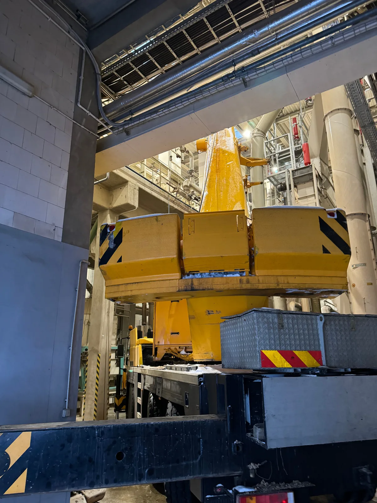 Żuraw samojezdny Liebherr pracuje między instalacjami w zakładzie produkcyjnym